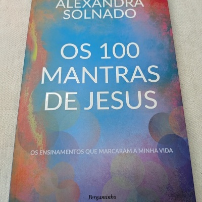 Capa de livro colorida com título Os 100 Mantras de Jesus e autor Alexandra Solnado.