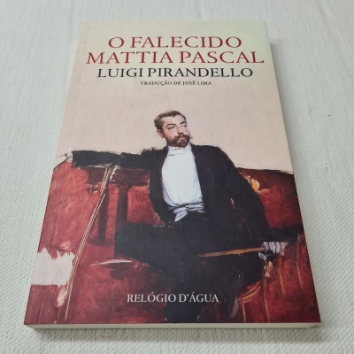 Capa de livro com título e autor, imagem de homem formal sentado num sofá vermelho