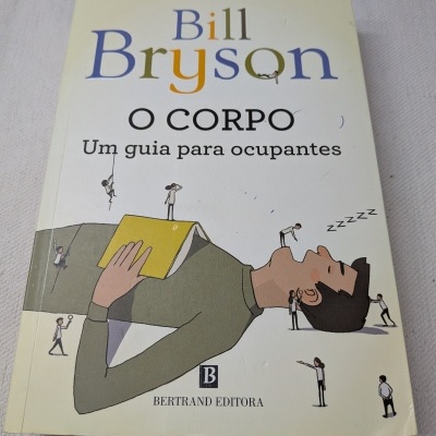 Capa de livro com título O Corpo de Bill Bryson e ilustração de pessoa deitada e pequenas figuras humanas.