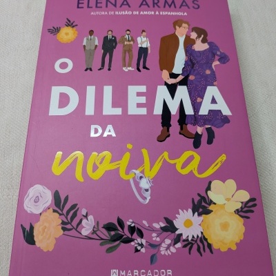 Livro cor-de-rosa com ilustrações de flores e personagens, e texto em branco e amarelo.