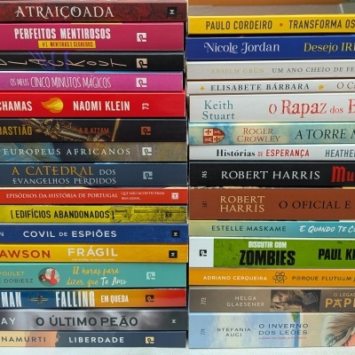 Pilhas de livros coloridos com títulos diversos em português e inglês