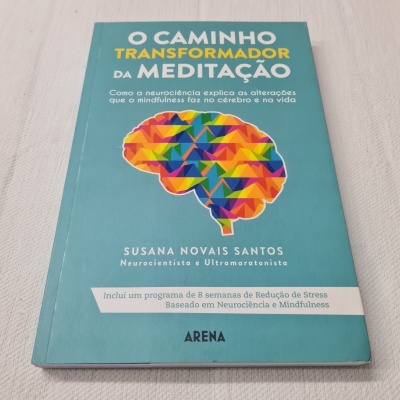 Livro azul com título sobre meditação e ilustração colorida de cérebro