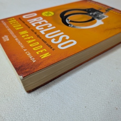 Livro O RECLUSO de capa laranja com imagem de algemas.
