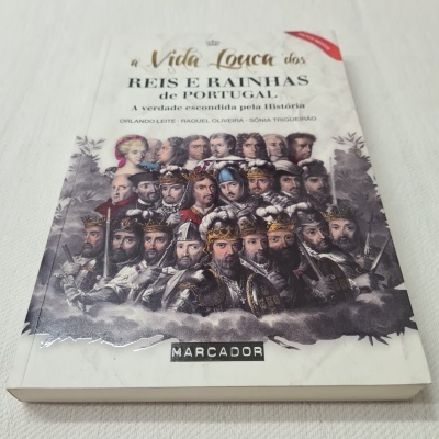 Livro com ilustração de várias figuras históricas e título sobre reis e rainhas de Portugal