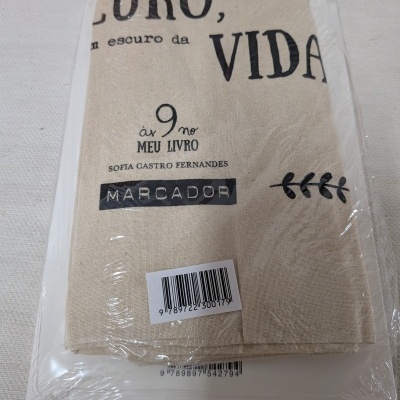 Marcador de livro de tecido bege com texto impresso a preto embalado em plástico