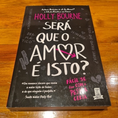 Livro com capa preta e texto colorido sobre uma mesa de madeira