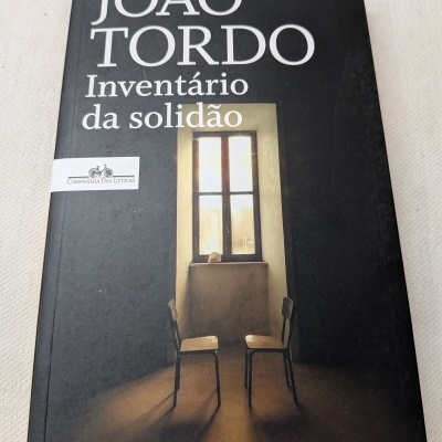 Capa de livro preta com título e imagem de duas cadeiras e janela