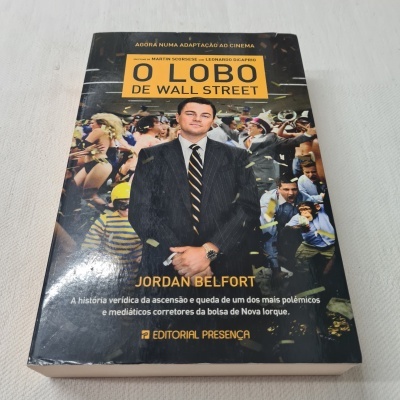 Capa de livro 'O LOBO DE WALL STREET' com homem de fato preto e multidão atrás
