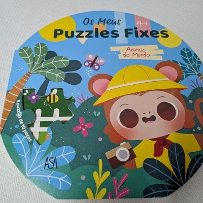 Caixa de puzzle redonda com desenho de macaco ilustrado e vegetação colorida, texto em português.