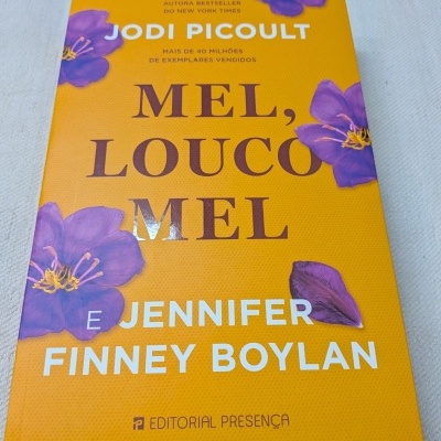 Capa de livro amarela com flores roxas e texto