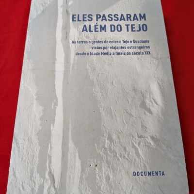 Livro branco texturizado com título azul sobre tecido vermelho