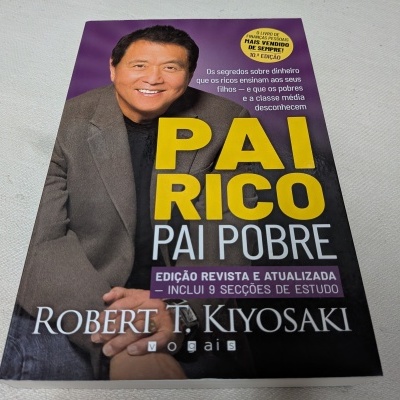 Livro 'PAI RICO PAI POBRE' de Robert T. Kiyosaki com capa predominantemente roxa e preta