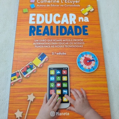 Capa de livro com título Educar na Realidade, ilustrações de brinquedos de madeira e mãos de criança.