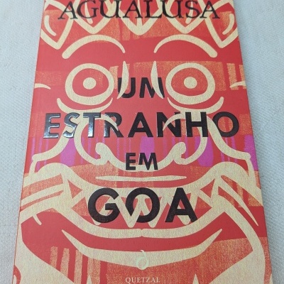 Capa de livro vermelho e dourado com título UM ESTRANHO EM GOA de José Eduardo Agualusa