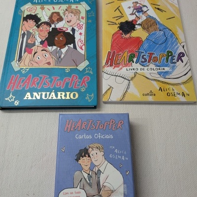 Três produtos Heartstopper de Alice Oseman com capas coloridas e ilustrações de personagens.