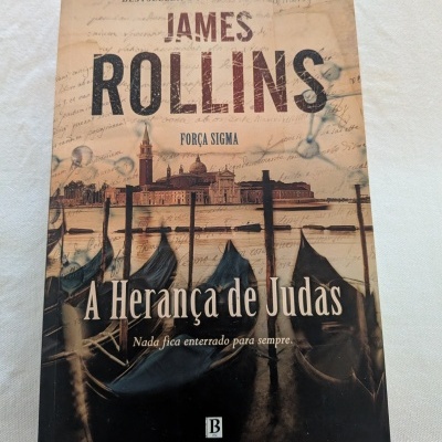 Capa de livro A Herança de Judas de James Rollins com imagem de barcos e edifícios históricos.