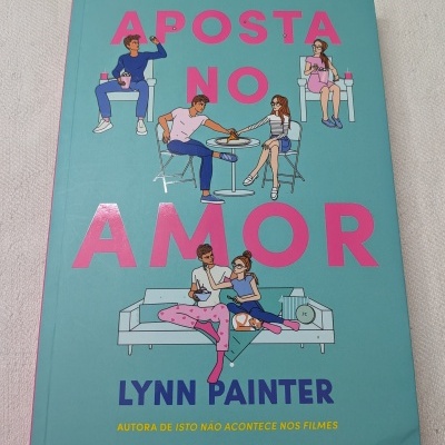 Capa de livro com fundo azul turquesa e título rosa APOSTA NO AMOR com ilustrações de casais.