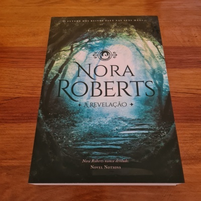 Capa do livro 'A Revelação' de Nora Roberts com floresta e caminho