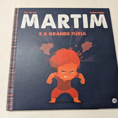Livro infantil Martim e a Grande Fúria capa dura azul escuro com criança irritada ruiva