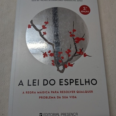 Capa de livro branco com título e ilustração de ramo com flores vermelhas sobre círculo prateado