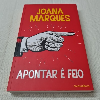 Livro vermelho com texto e ilustração de mão apontando