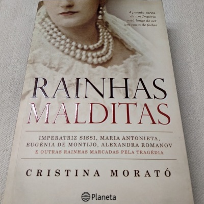 Capa do livro Rainhas Malditas com imagem de mulher e colar de pérolas