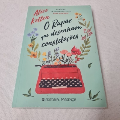 Capa de livro 'O Rapaz que desenhava constelações' de Alice Kellen com máquina de escrever vermelha e flores