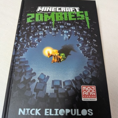 Livro Minecraft Zombies com capa preta e texto em verde e branco