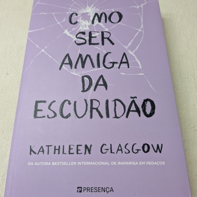 Capa lilás de livro com texto preto e branco sobre tecido claro