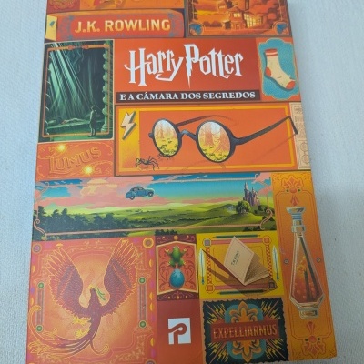 Capa de livro Harry Potter e a Câmara dos Segredos com várias ilustrações coloridas e nome do autor.