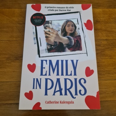 Capa do livro Emily in Paris com corações vermelhos e foto de mulher a tirar selfie
