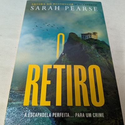 Capa do livro O RETIRO de Sarah Pearse com penhasco e casa no topo.