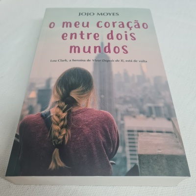Capa do livro 'o meu coração entre dois mundos' de Jojo Moyes com imagem de mulher de costas e cidade ao fundo
