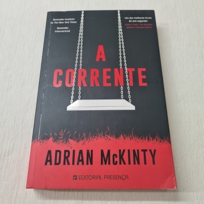 Capa do livro 'A Corrente' de Adrian McKinty com balanço branco e texto em vermelho e branco