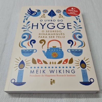 Capa do livro 'O Livro do Hygge' com ilustrações coloridas e selo vermelho