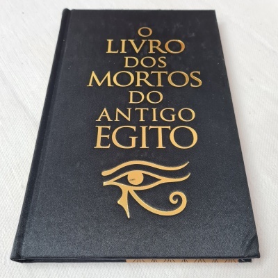 Livro com capa preta e letras douradas 'O LIVRO DOS MORTOS DO ANTIGO EGITO' com símbolo do Olho de Hórus.