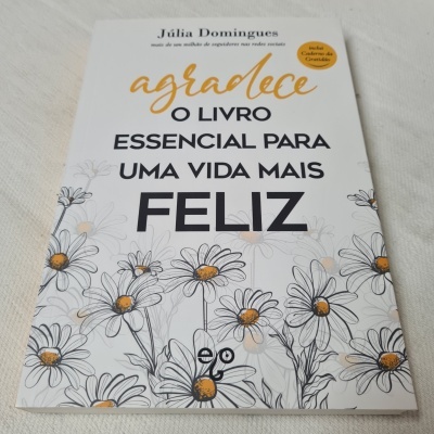 Capa de livro com flores brancas e amarelas e texto em preto e dourado