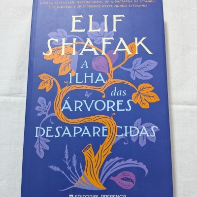 Capa de livro azul com ilustração de árvore laranja e violeta e título em letras azuis e brancas.