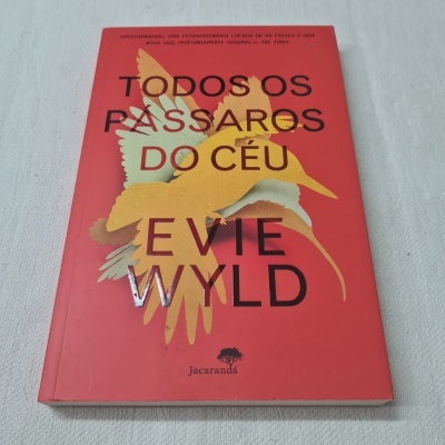 Livro vermelho com título e ilustração de pássaros na capa.
