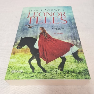 Capa do livro Leonor Teles com mulher de capa vermelha a cavalo preto num campo verde