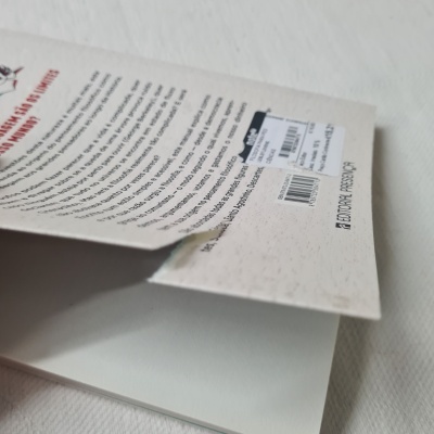 Livro aberto com capa traseira branca e texto preto e vermelho.