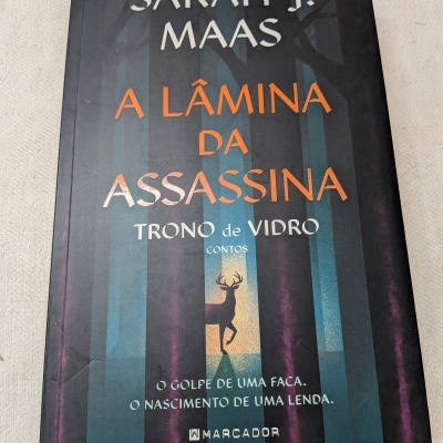Capa do livro A Lâmina da Assassina com silhueta de veado e texto em várias cores