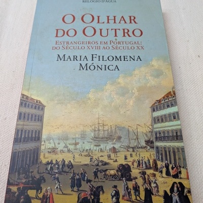 Livro com capa ilustrada de cena histórica urbana e marítima, texto vermelho e preto na capa.