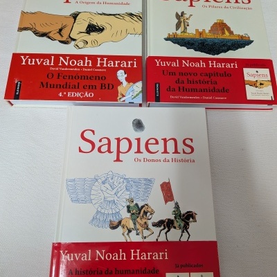 Três livros de capa dura Sapiens em português com capas ilustradas e faixas vermelhas contendo texto.