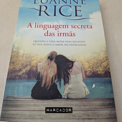 Capa de livro com duas mulheres sentadas de costas à beira de um lago