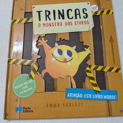 Livro infantil Trincas o monstro dos livros com ilustração de monstro amarelo e textos em português.