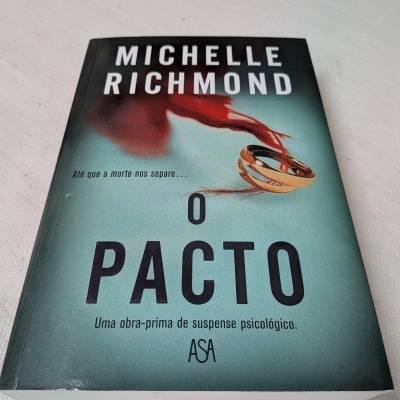 Capa do livro O PACTO de Michelle Richmond com duas alianças douradas e laço vermelho