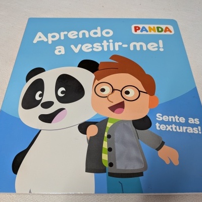 Capa de livro infantil azul com panda e criança com óculos, texto 'Aprendo a vestir-me!' e 'Sente as texturas!'