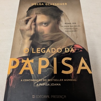 Capa de livro O LEGADO DA PAPISA com mulher de véu e texto em dourado e preto