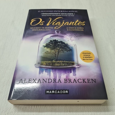 Capa do livro 'Os Viajantes' de Alexandra Bracken com árvore sob campânula de vidro e fundo roxo